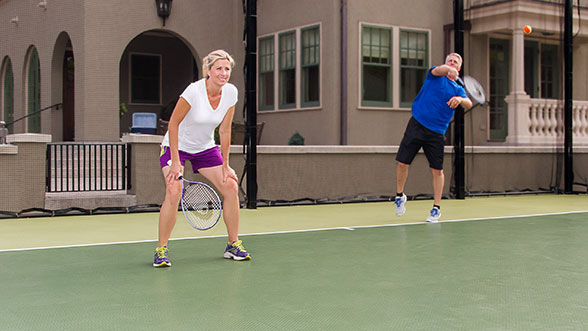 A couple is playing tennis on their home tennis court.