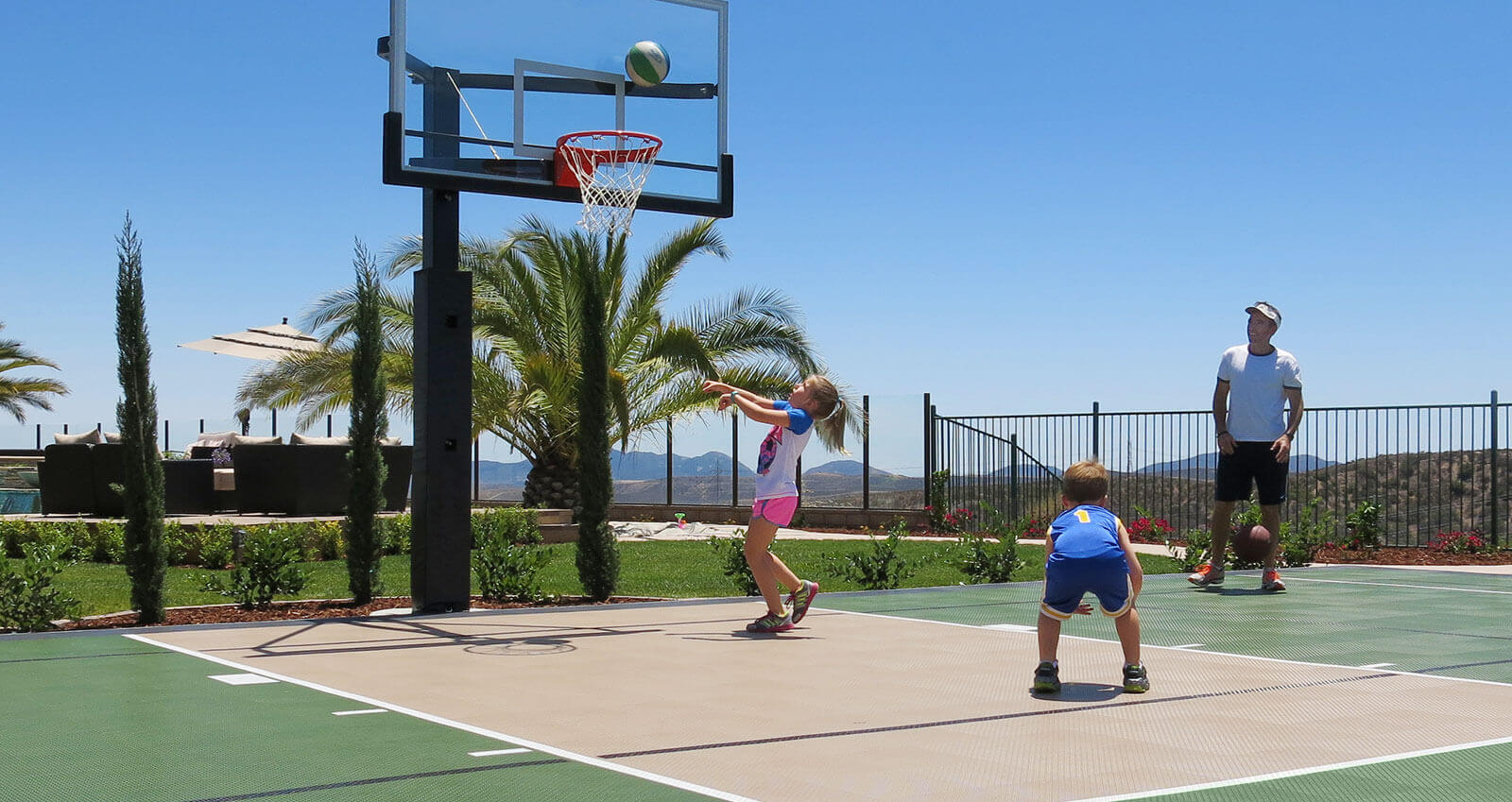 A family is playing basketball on their backyard court.